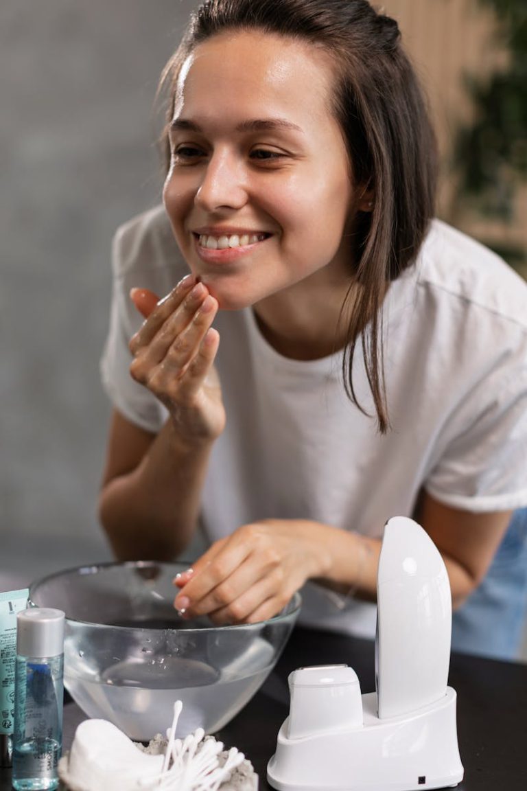 Smiling woman applying facial cream as part of her daily skincare routine.